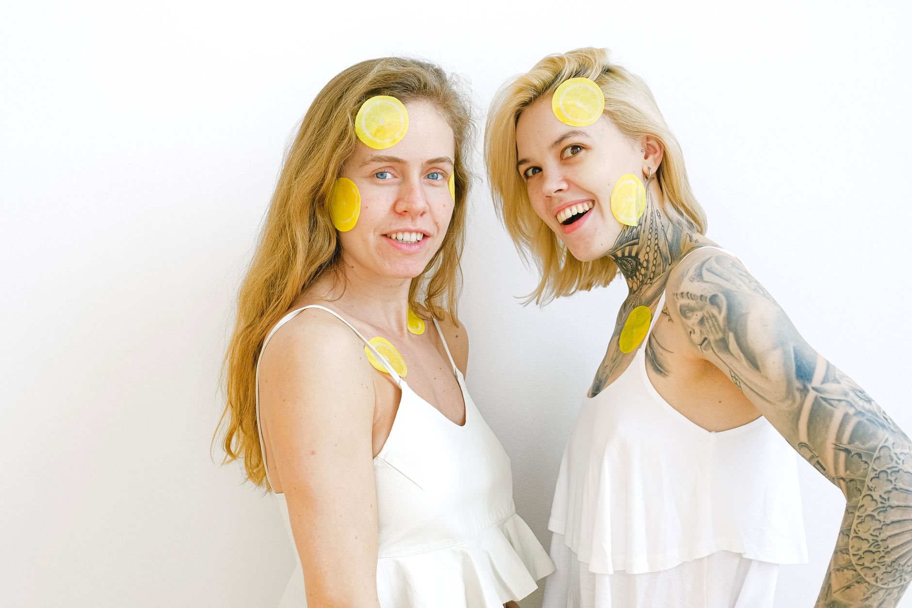 Two women laughing together with lemon slices, expressing joy and connection