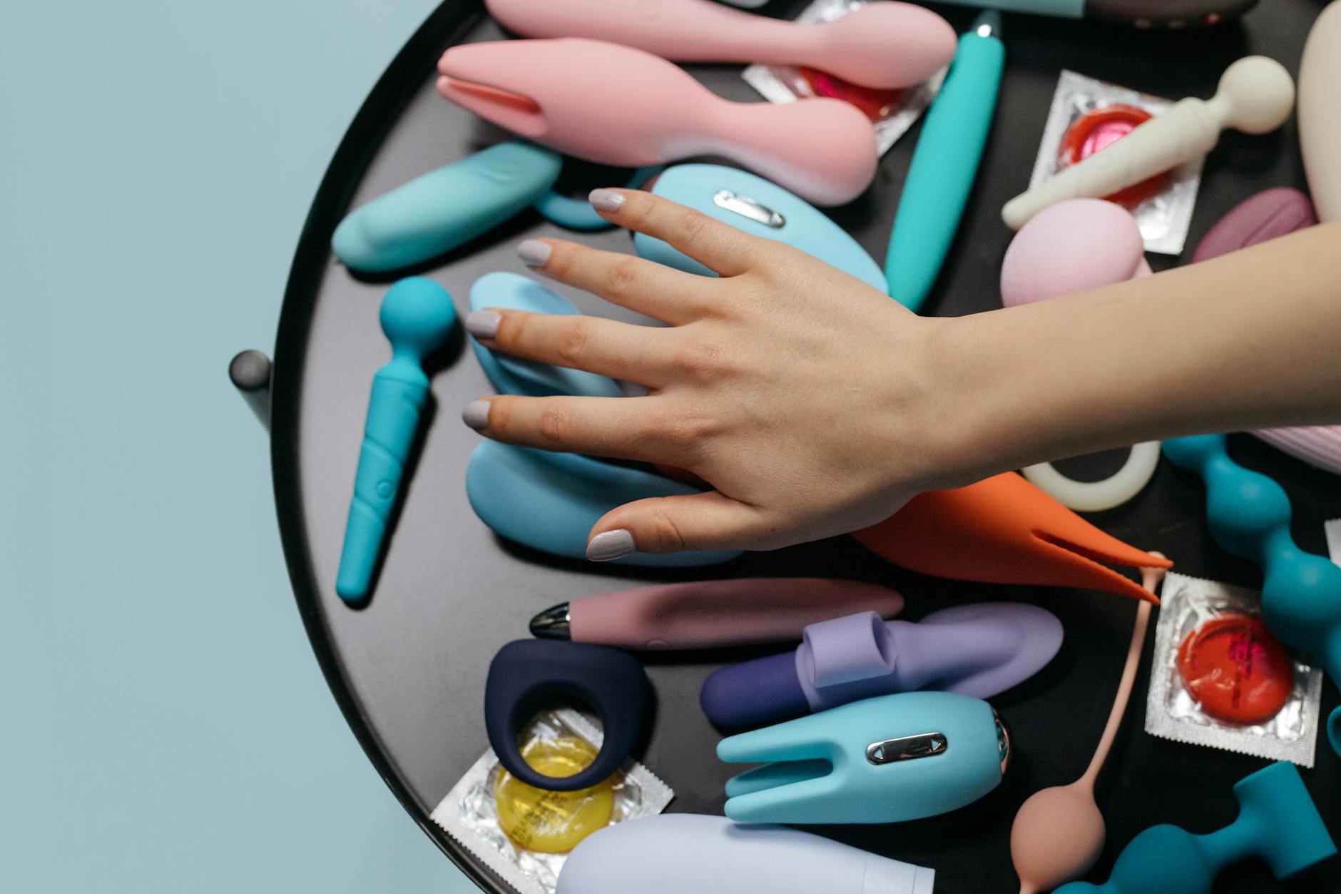 Una mano raggiunge su una varietà di giocattoli per adulti colorati disposti su un tavolo