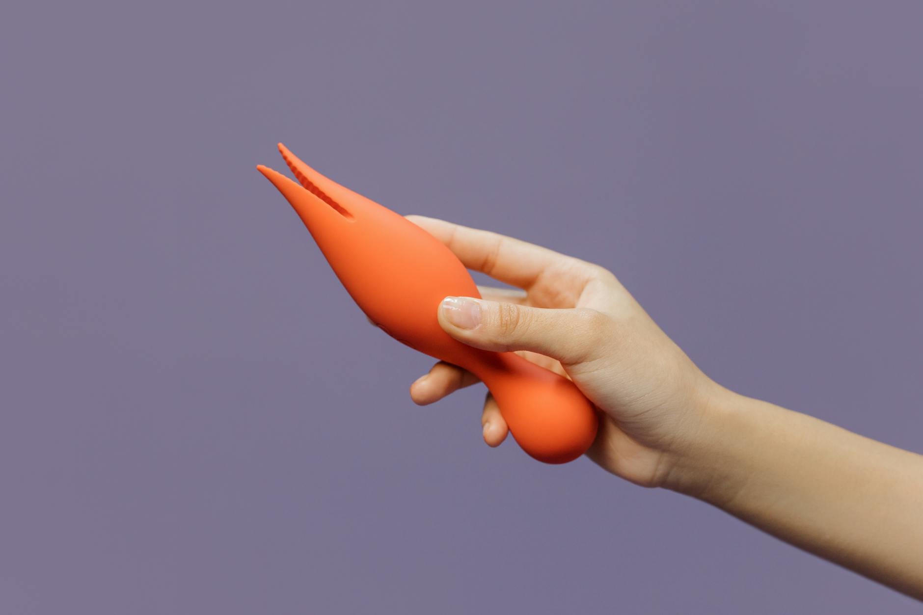 Mano che tiene un vibratore al limone colorato su sfondo minimalista, mostrando sensualità moderna