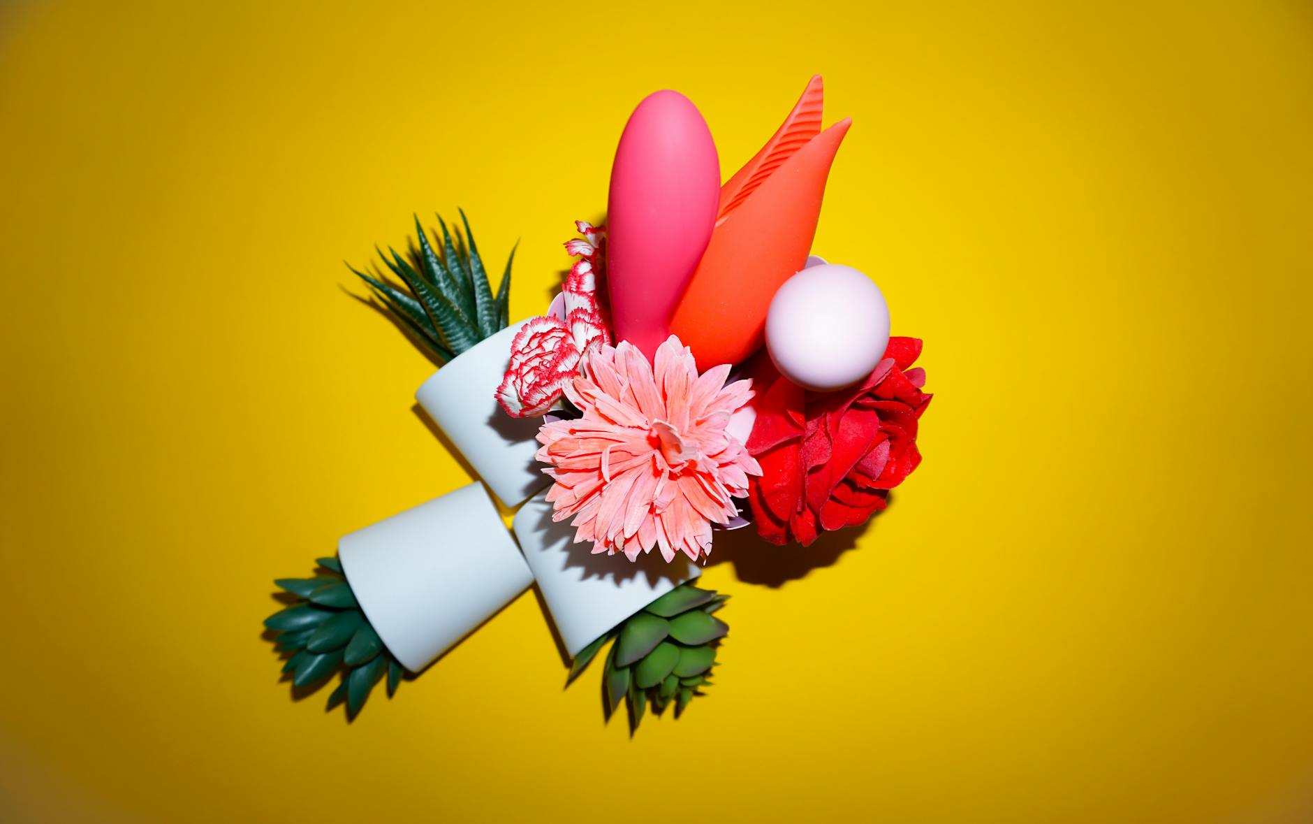 Colorful clitoral vibrators and adult toys arranged on a bright yellow background